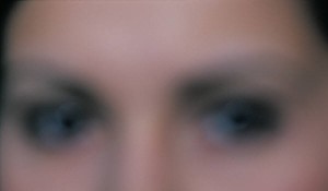 A blurred image of a woman's eyes and the bridge of her nose.